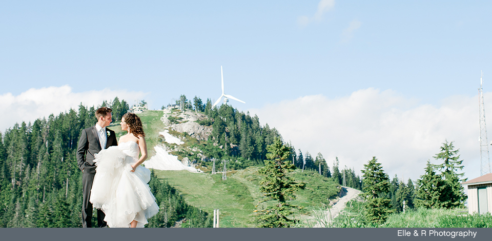 couple in the summer at Grouse Mountain with The Eye of the Wind behind them