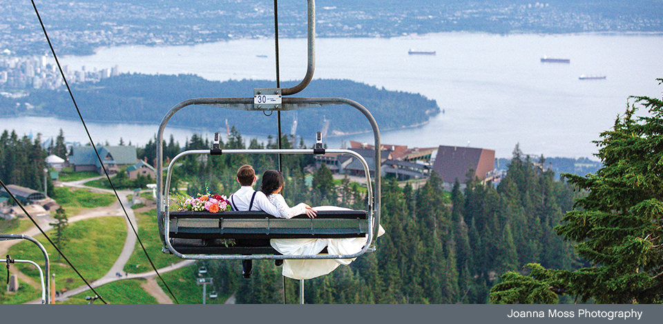 wedding day couple riding chairlift down to Chalet with view of Vancouver in background