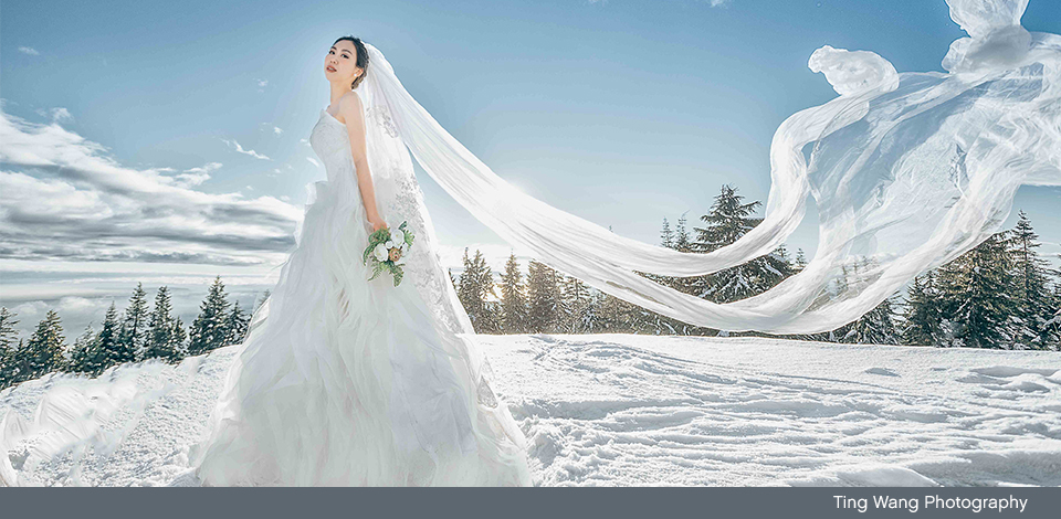 bride at the top of Grouse Mountain in the winter with veil blowing in the wind